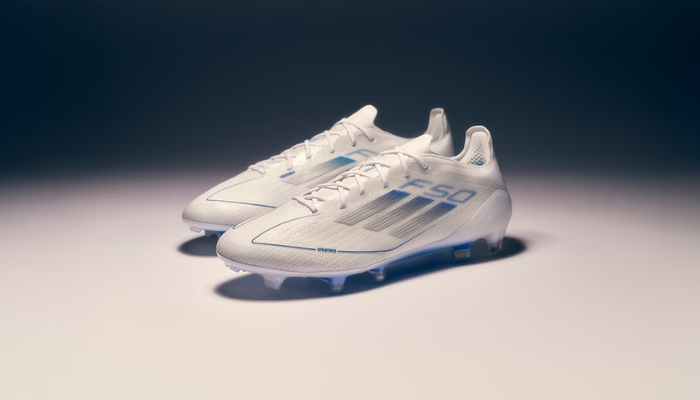 Chuteira Adidas F50 Elite FG Polar Victory 2025, modelo com cadarço, cor branca perolada com detalhes em azul. Cabedal Fibertouch ultraleve, Sprintweb 3D para maior controle de bola, Compression Fit Tunnel Tongue para ajuste perfeito e placa Sprintframe 360 para cortes rápidos e mudanças de direção ágeis.